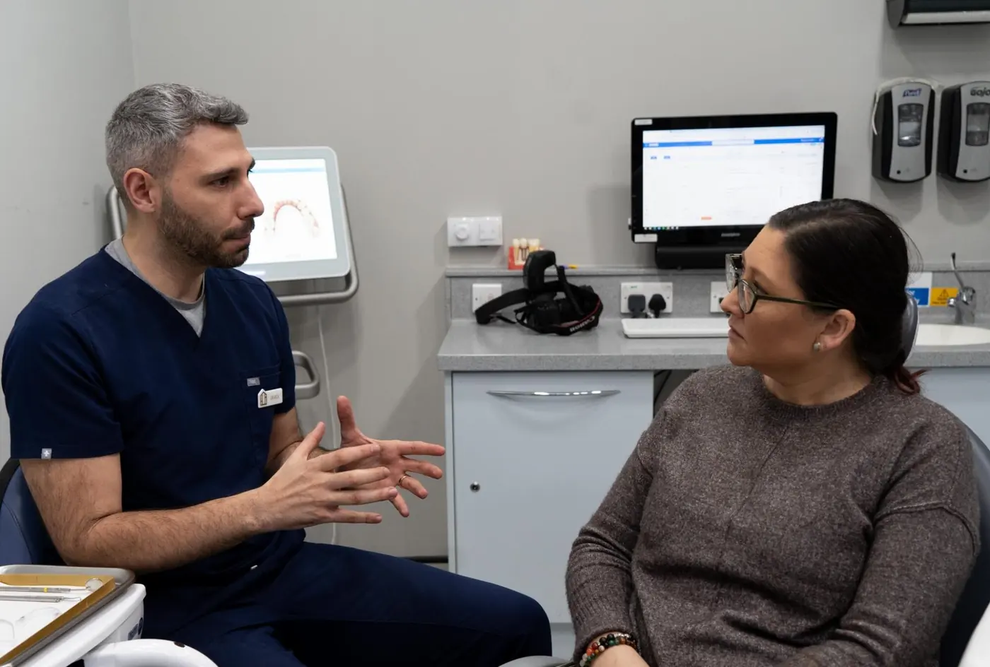 Dr Riccardo Lo Giudice talking through treatment with a patient beside an Invisalign scanner